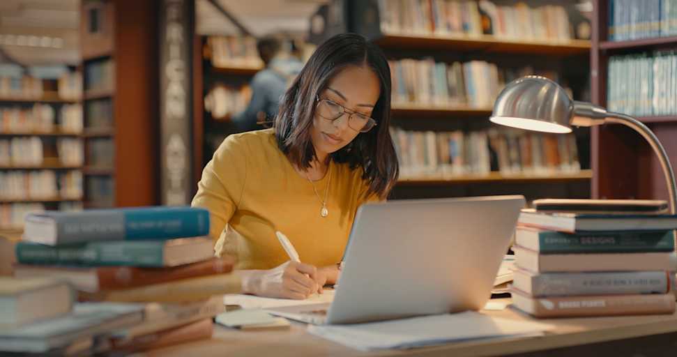 College student studying in library with laptop