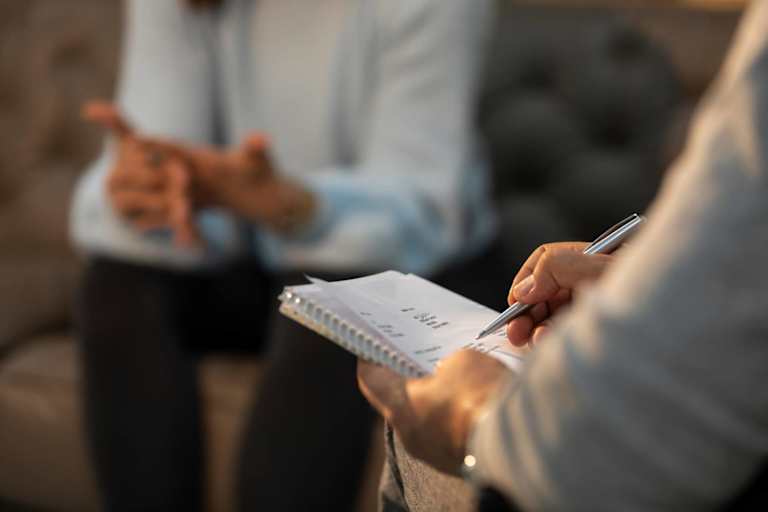 Male psychologist listening and taking notes during a cognitive assessment with a patient.